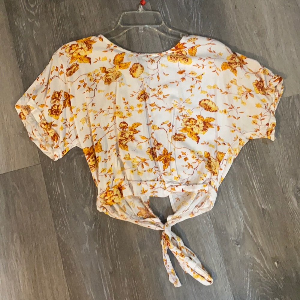 This cute top has never been worn and has a cute tie to add something extra